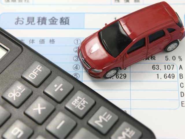 電卓と見積書を赤い車
